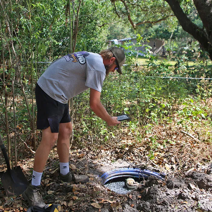 Technician inspecting an open septic tank during a home-sale inspection in Western North Carolina